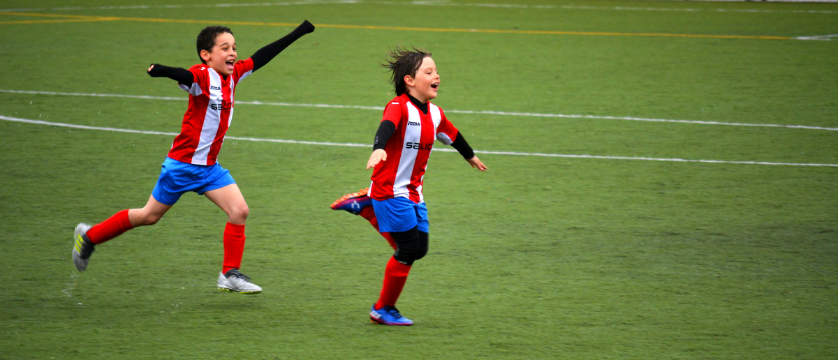 Kinder haben Spaß an Sport und Bewegung und rennen über den Fußballplatz