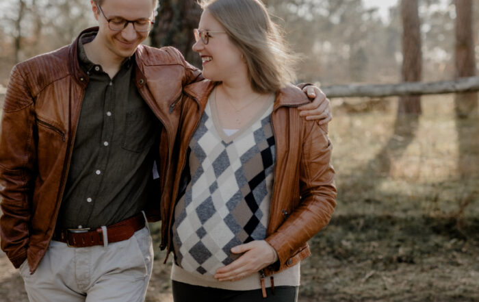 TALENT SAFARI erwartet Zuwachs, Hand in Hand mit der Natur. Die werdende Mama Kathi hält schützend ihren Babybauch, während der werdende Papa Tom sie liebevoll umarmt.